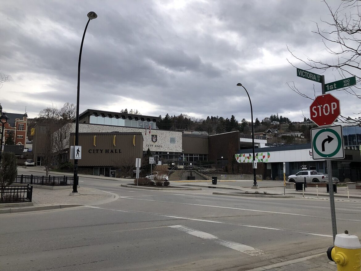 City Hall building on a street corner with a stop sign and a right-turn arrow sign, under a cloudy sky.