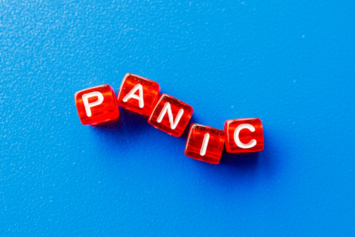 Red transparent letter cubes spelling the word PANIC on a bright blue background