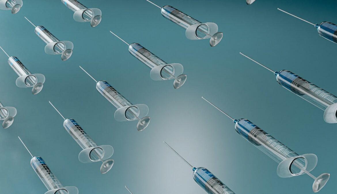 Multiple syringes floating diagonally across a teal background, tips exposed.