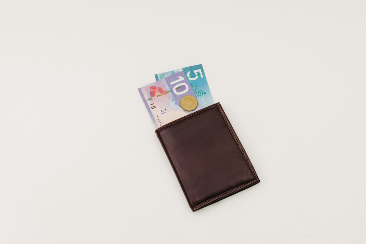 Brown leather wallet with euro banknotes partially visible and a coin peeking out