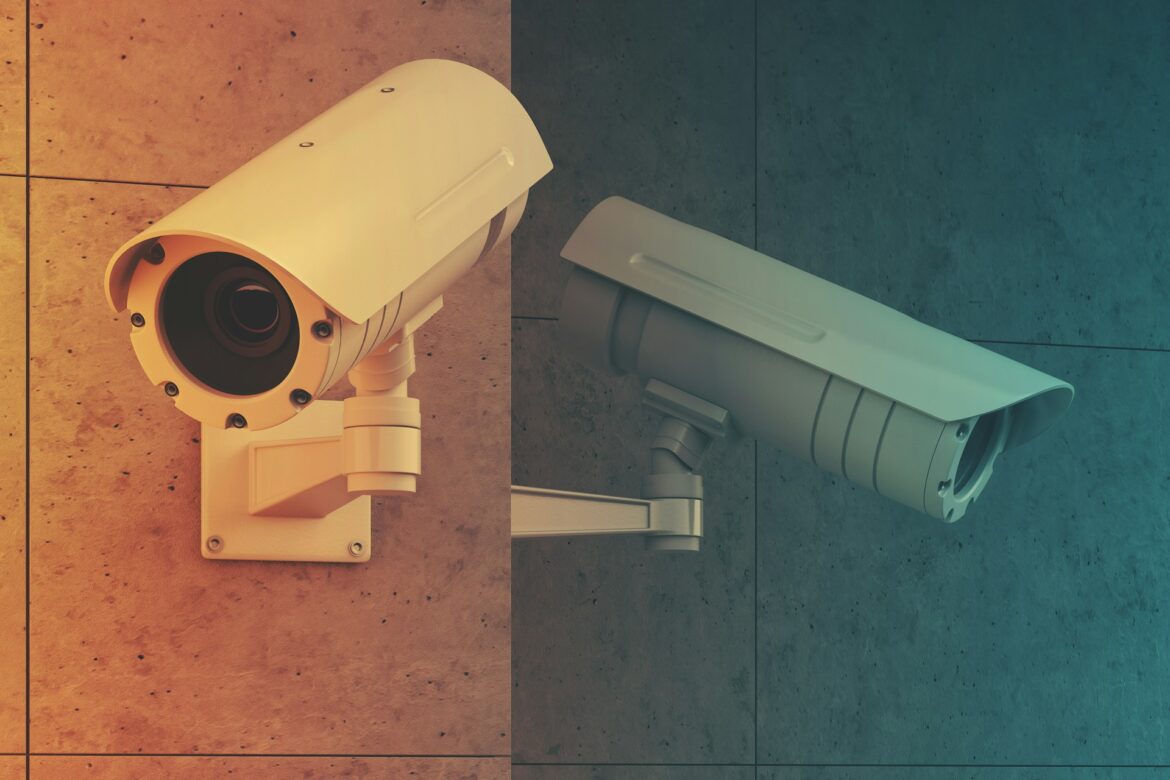 Two security cameras mounted on a tiled wall, with orange tint on the left and teal tint on the right, overlooking an area.