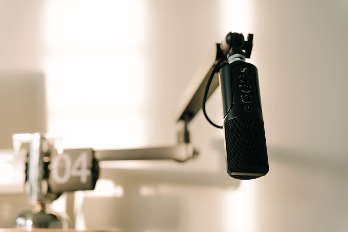 Blue USB microphone hanging from a boom arm in a recording studio, ready for voice capture
