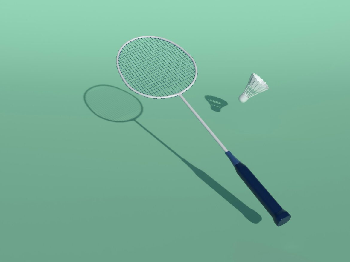 Overhead view of a white badminton racket with a blue grip and a white shuttlecock on a green surface, with shadows nearby.